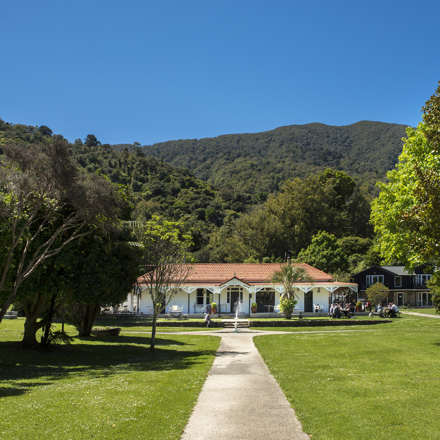 Large sweeping lawns and the front of historic Howden House with its distinctive verandah and orange tiled roof, in the Marlborough Sounds at the top of New Zealand's South Island.