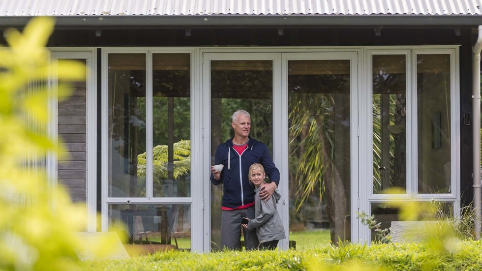 A father and daughter relax outside an Endeavour Suite at Furneaux Lodge in the Marlborough Sounds at the top of New Zealand's South Island.