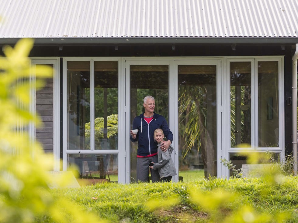 A father and daughter relax outside an Endeavour Suite at Furneaux Lodge in the Marlborough Sounds at the top of New Zealand's South Island.