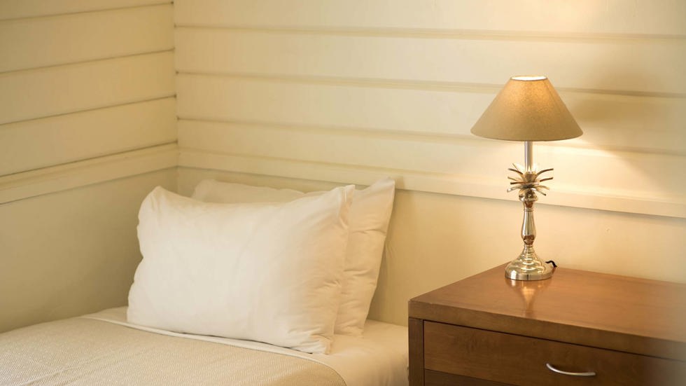 A single bed in a Cook's Cottage with natural decor details at Furneaux Lodge in the Marlborough Sounds at the top of New Zealand's South Island.