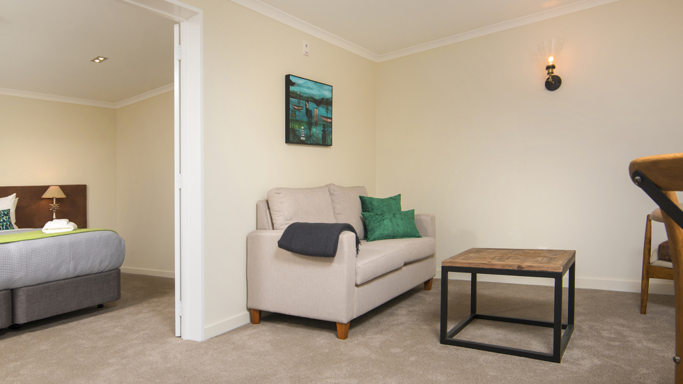 A Tobias Junior Suite living area is situated close to the bedroom area at Furneaux Lodge in the Marlborough Sounds, New Zealand.