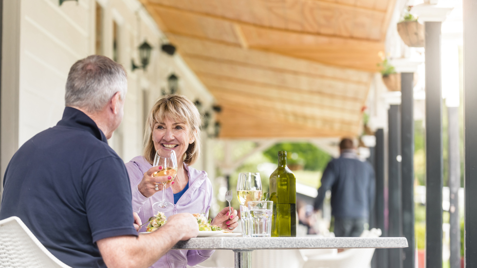 A couple dines at a table on the verandah at the Furneaux Lodge Restaurant in the Marlborough Sounds at the top of New Zealand's South Island.