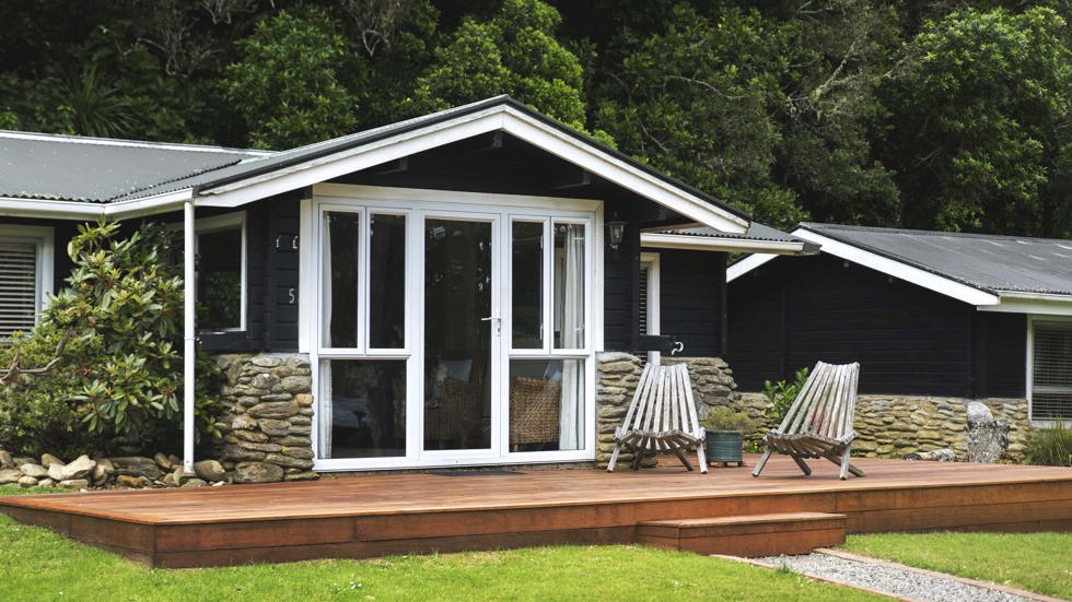 A Cook's Cottage exterior with private deck and outdoor seating at Furneaux Lodge in the Marlborough Sounds at the top of New Zealand's South Island.