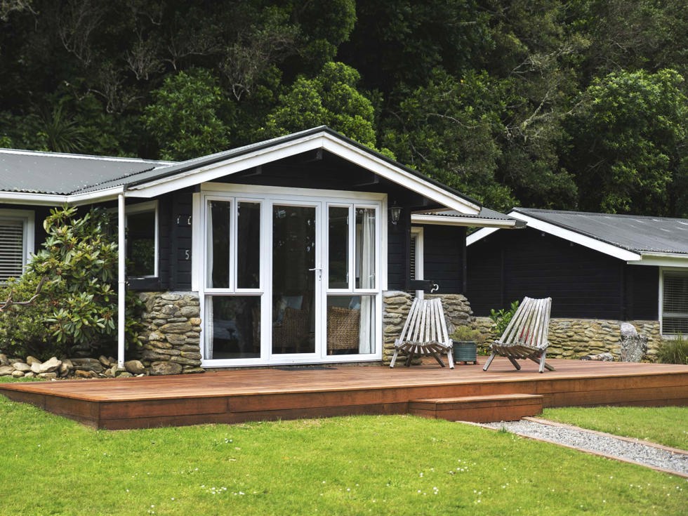 A Cook's Cottage exterior with private deck and outdoor seating at Furneaux Lodge in the Marlborough Sounds at the top of New Zealand's South Island.