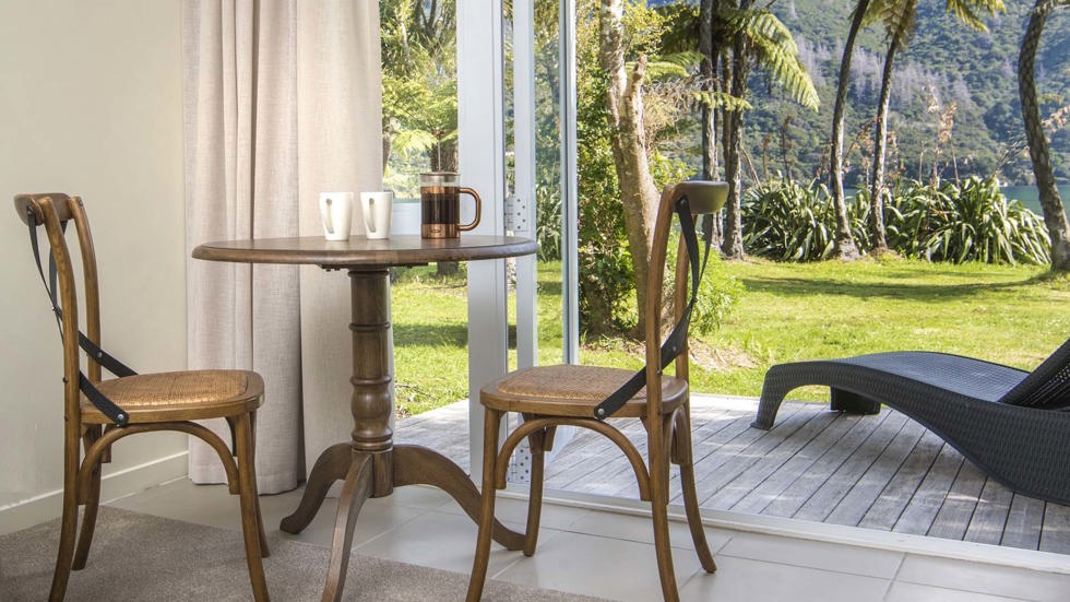 An Endeavour Suite dining area with cups of coffee and a sea view at Furneaux Lodge in the Marlborough Sounds at the top of New Zealand's South Island.