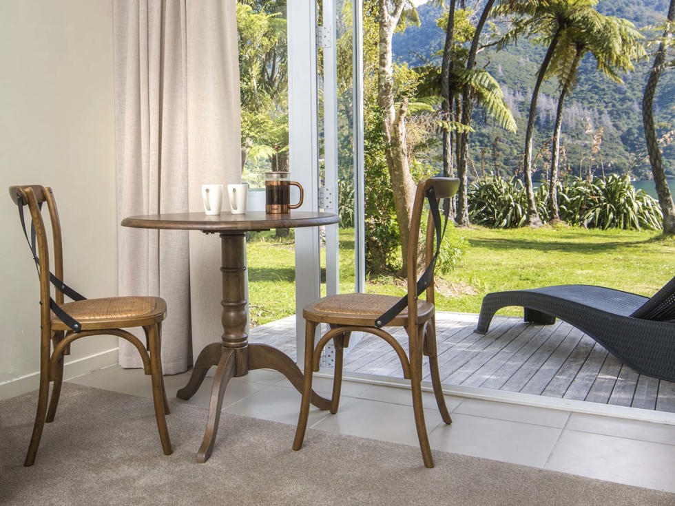 An Endeavour Suite dining area with cups of coffee and a sea view at Furneaux Lodge in the Marlborough Sounds at the top of New Zealand's South Island.