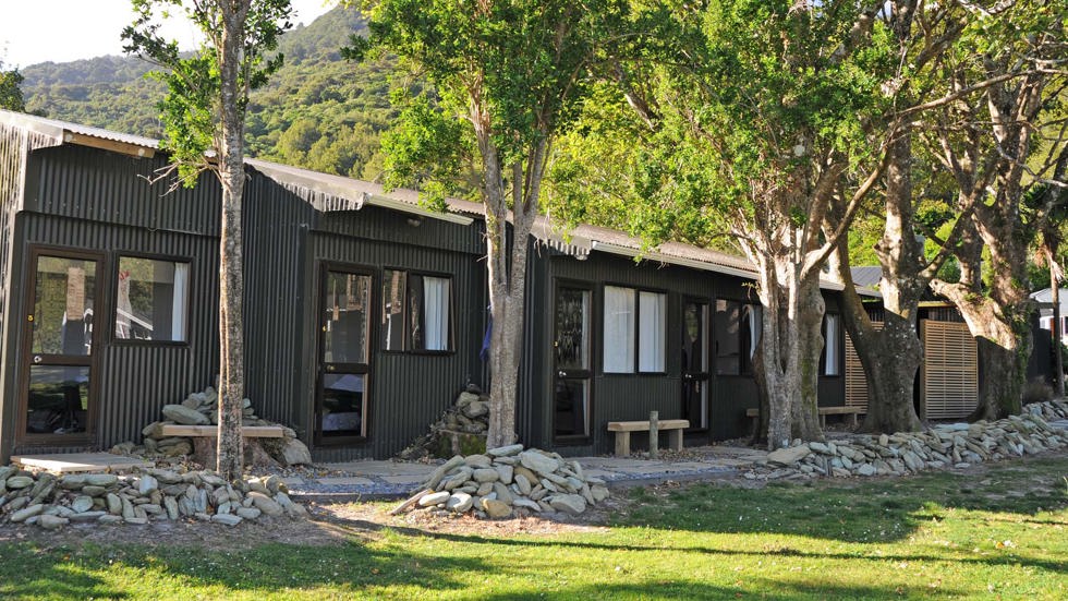 Hiker's cabins lined up behind trees at Furneaux Lodge in the Marlborough Sounds at the top of New Zealand's South Island.