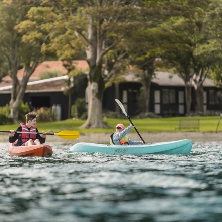 Two boys paddle kayaks in front of Furneaux Lodge in New Zealand's Marlborough Sounds.