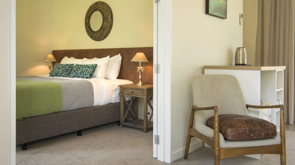 The bedroom area of an Endeavour Suite is situated beside the main living area at Furneaux Lodge in the Marlborough Sounds, New Zealand.