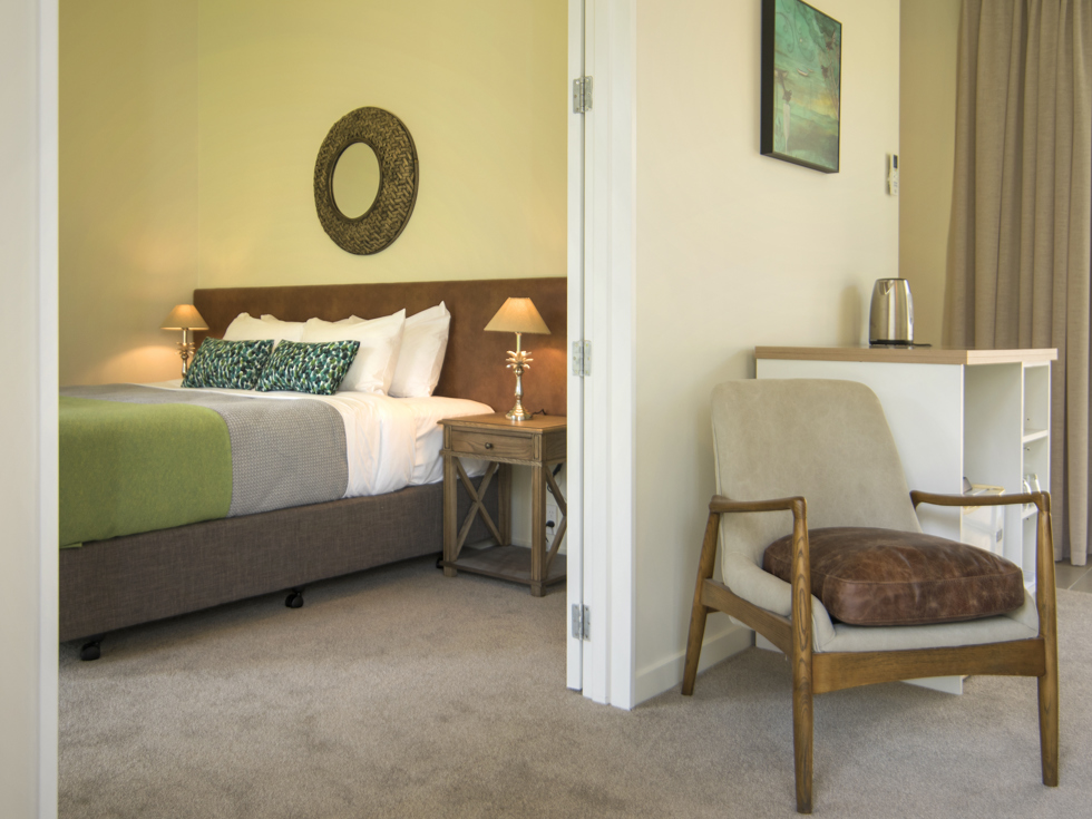 The bedroom area of an Endeavour Suite is situated beside the main living area at Furneaux Lodge in the Marlborough Sounds, New Zealand.