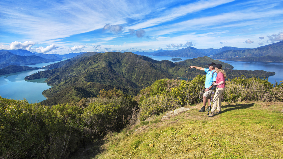 Two people walk on the northern Queen Charlotte Track in the Marlborough Sounds, New Zealand.