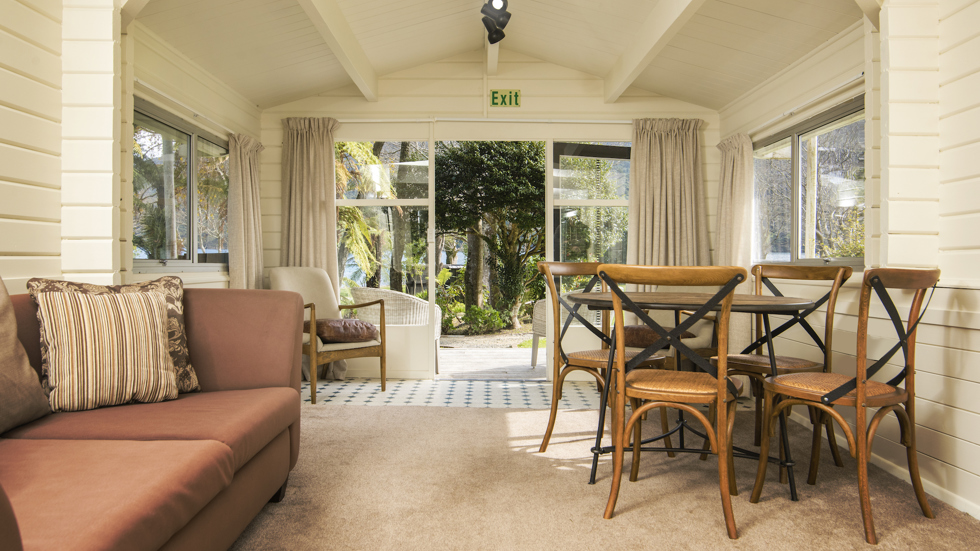 A Cook's Cottage lounge and dining area looking out over the Furneaux Lodge grounds at Furneaux Lodge in the Marlborough Sounds, New Zealand.