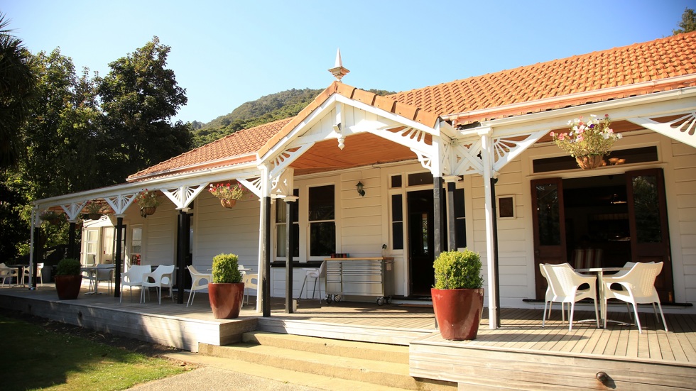 Tables for dining at the Restaurant and Bar are available outside on the homestead verandah at Furneaux Lodge in the Marlborough Sounds, New Zealand.