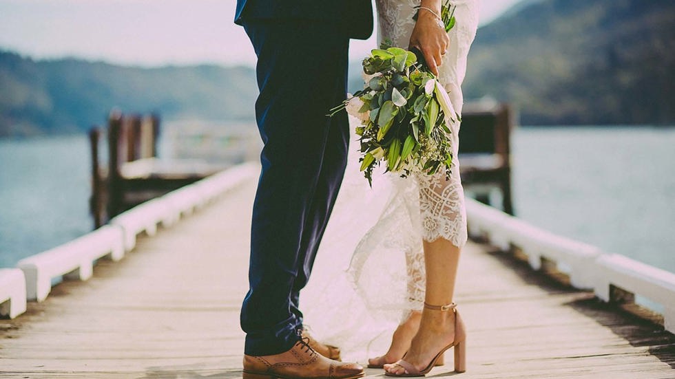 A newly married couple stand together on the Furneaux Lodge jetty in the Marlborough Sounds in New Zealand's top of the South Island