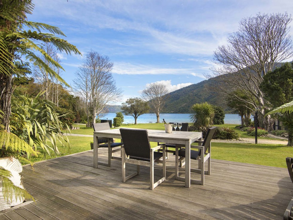 An outdoor dining table on a private Cook's Cottage deck overlooking the Endeavour Inlet Bay at Furneaux Lodge in the Marlborough Sounds at the top of New Zealand's South Island.