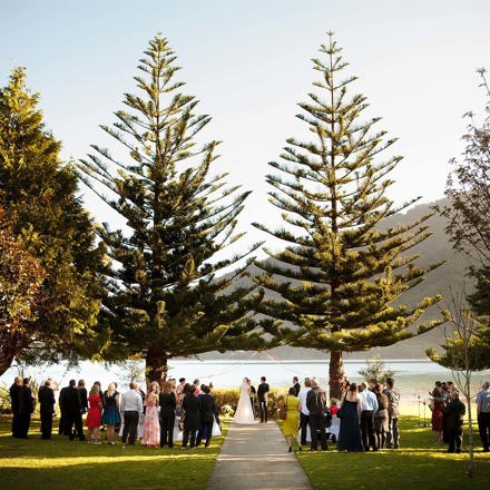 A bride and groom get married at Furneaux Lodge with Endeavour Inlet background in the Marlborough Sounds in New Zealand's top of the South Island