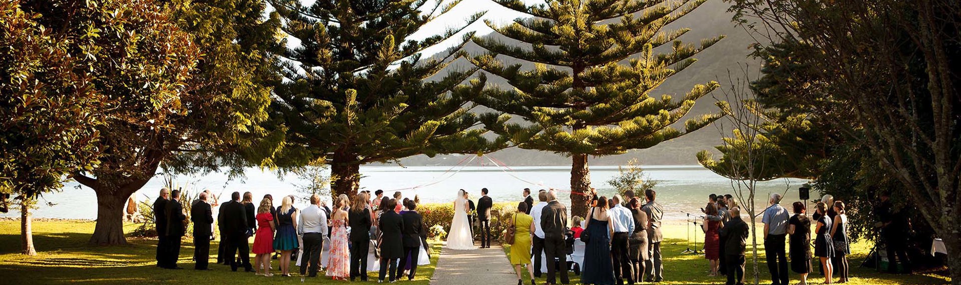 A bride and groom get married at Furneaux Lodge with Endeavour Inlet background in the Marlborough Sounds in New Zealand's top of the South Island