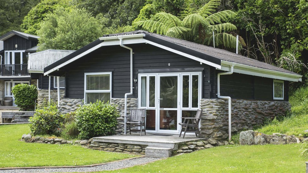 A Cook's Cottage surrounded by lush green native bush at Furneaux Lodge in the Marlborough Sounds at the top of New Zealand's South Island.