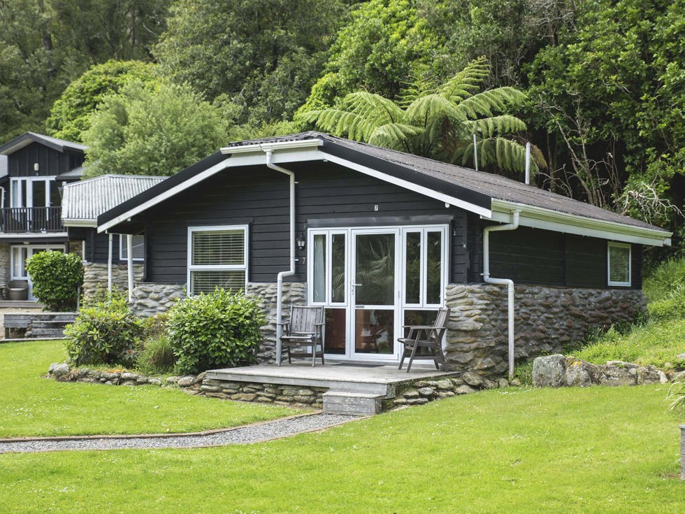 A Cook's Cottage surrounded by lush green native bush at Furneaux Lodge in the Marlborough Sounds at the top of New Zealand's South Island.