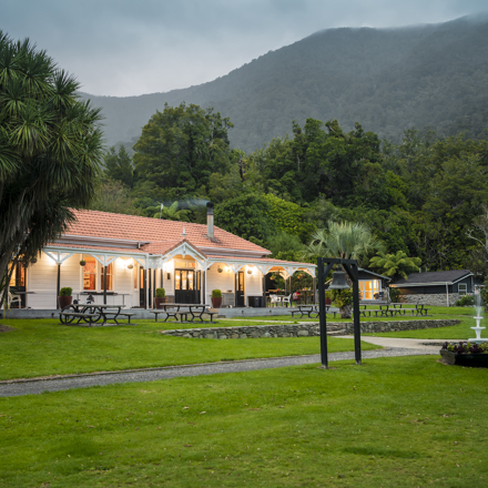 The front of historic Howden House with orange tiled roof and lawn in front, in the Marlborough Sounds at the top of New Zealand's South Island.