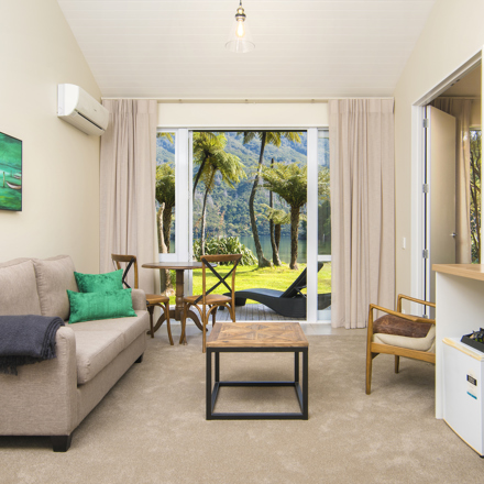 The main living and dining area of an Endeavour Suite looking out to the water views of Endeavour Inlet at Furneaux Lodge in the Marlborough Sounds, New Zealand.