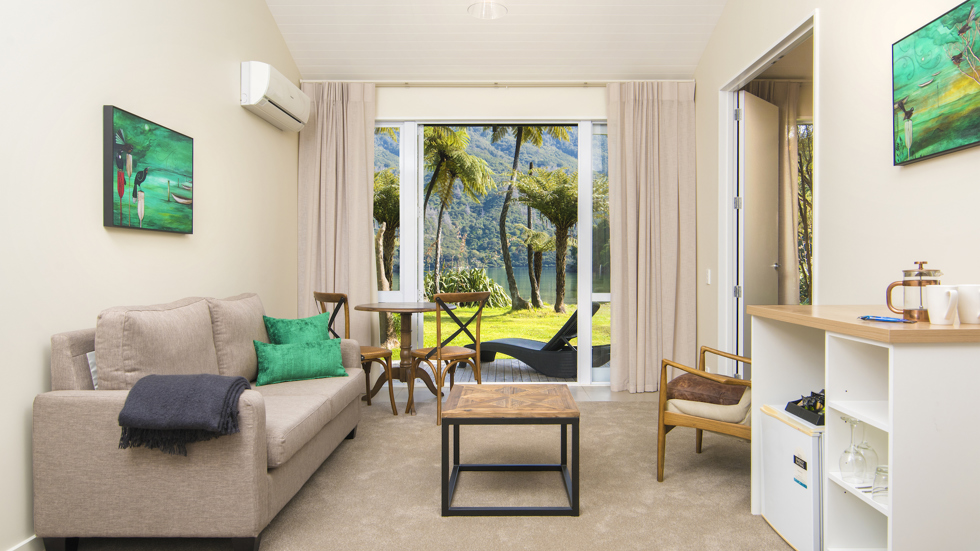 The main living and dining area of an Endeavour Suite looking out to the water views of Endeavour Inlet at Furneaux Lodge in the Marlborough Sounds, New Zealand.