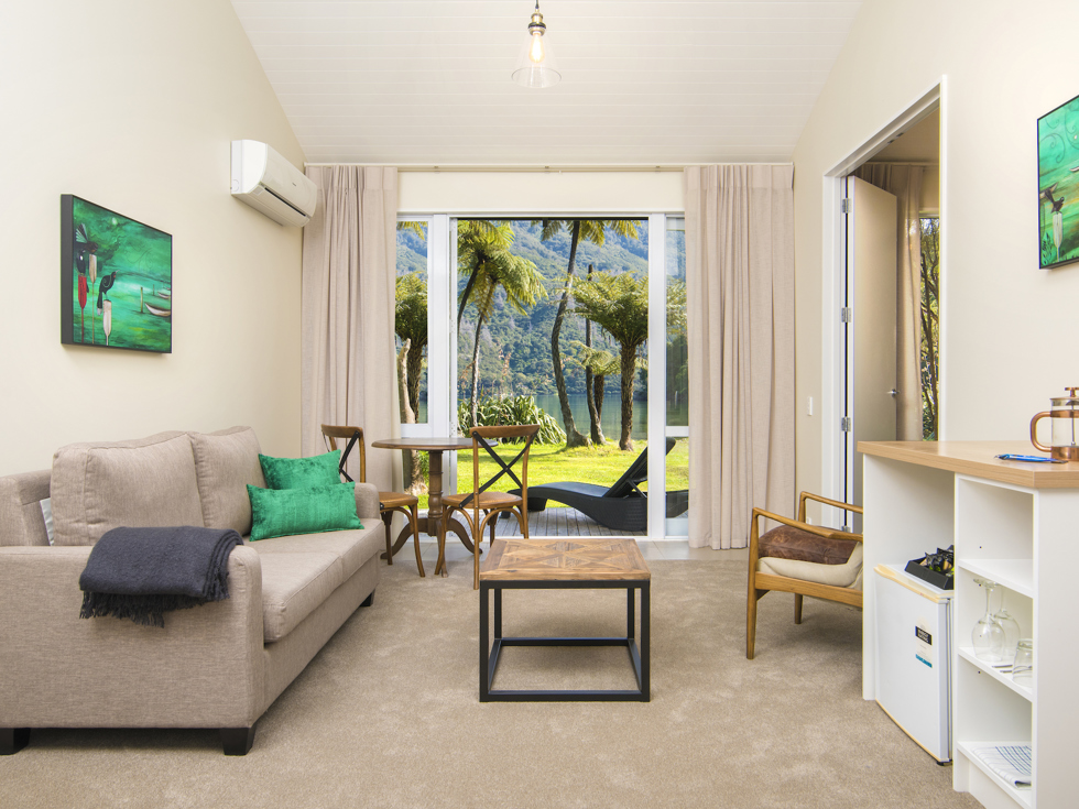 The main living and dining area of an Endeavour Suite looking out to the water views of Endeavour Inlet at Furneaux Lodge in the Marlborough Sounds, New Zealand.