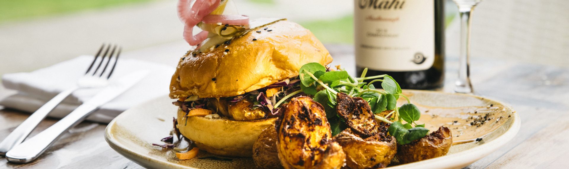 Gourmet chickpea and pumpkin burger with potatoes served with a glass of Mahi Sauvignon Blanc at the Furneaux Lodge Restaurant in the Marlborough Sounds at the top of New Zealand's South Island.